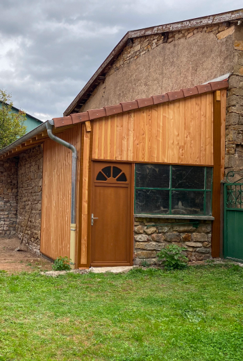 Petite construction en bois avec porte et fenêtre, toiture en tuiles rouges