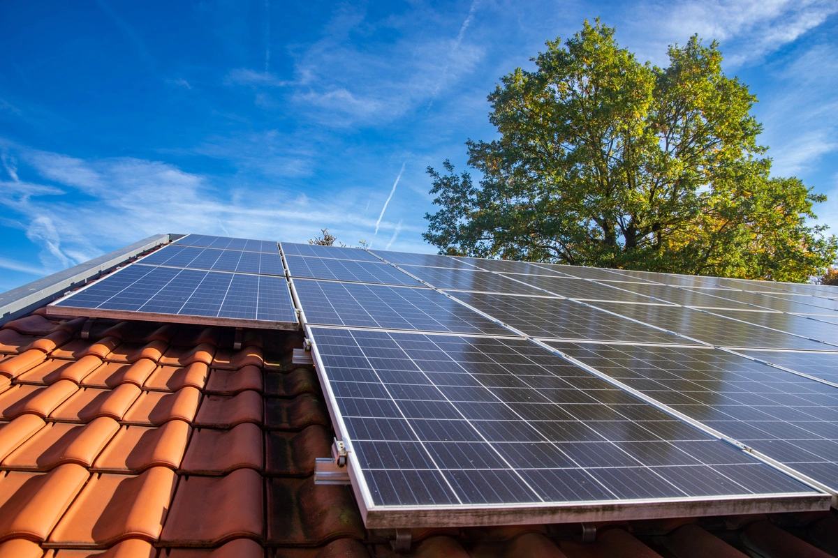 Panneaux photovoltaïques sur toit en tuiles rouges sous un ciel bleu